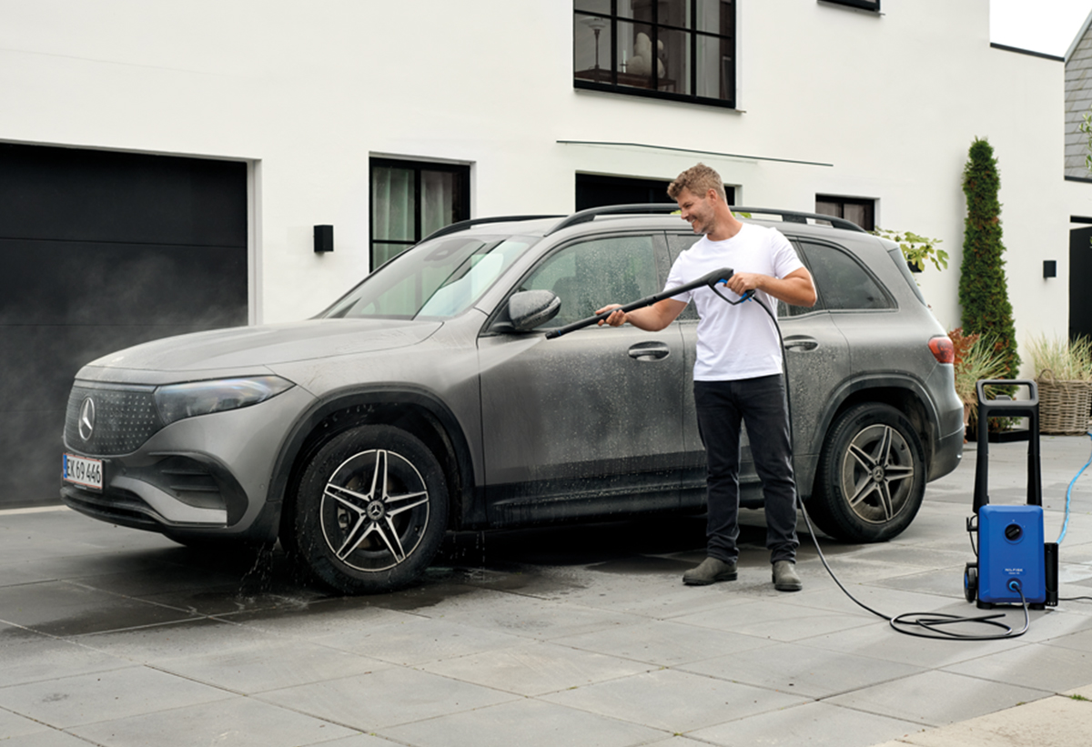 Απεικονίζεται άνδρας να χρησιμοποιεί το μηχάνημα για να πλύνει αυτοκίνητο.